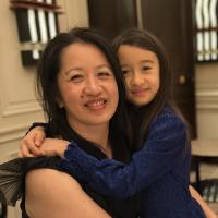 Warm indoor photo of smiling Chutharat Sae Tong and daughter hugging, girl in blue sweater